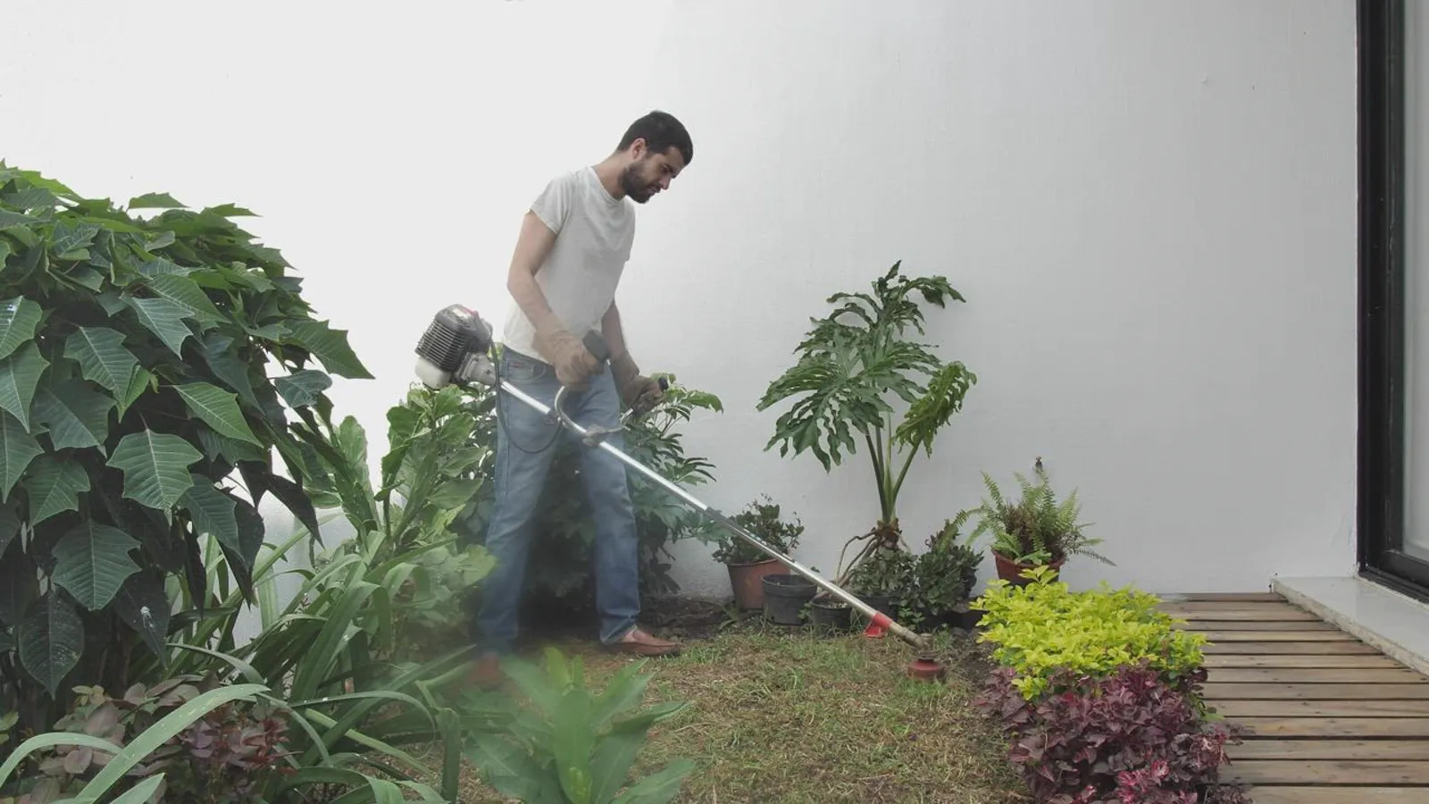 Man using a string trimmer along a landscaped garden border