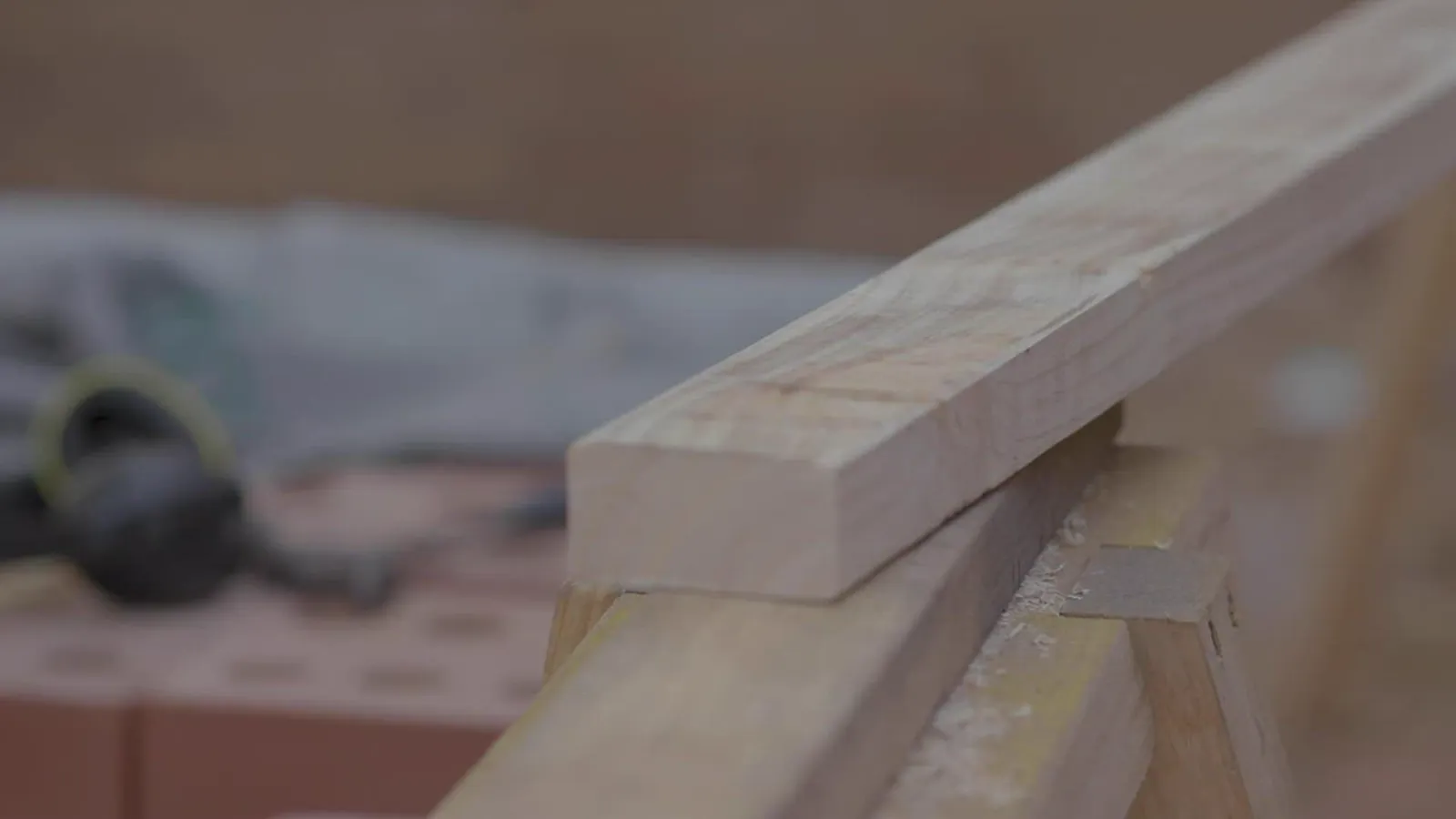Measured length of lumber resting on sawhorses in a workshop