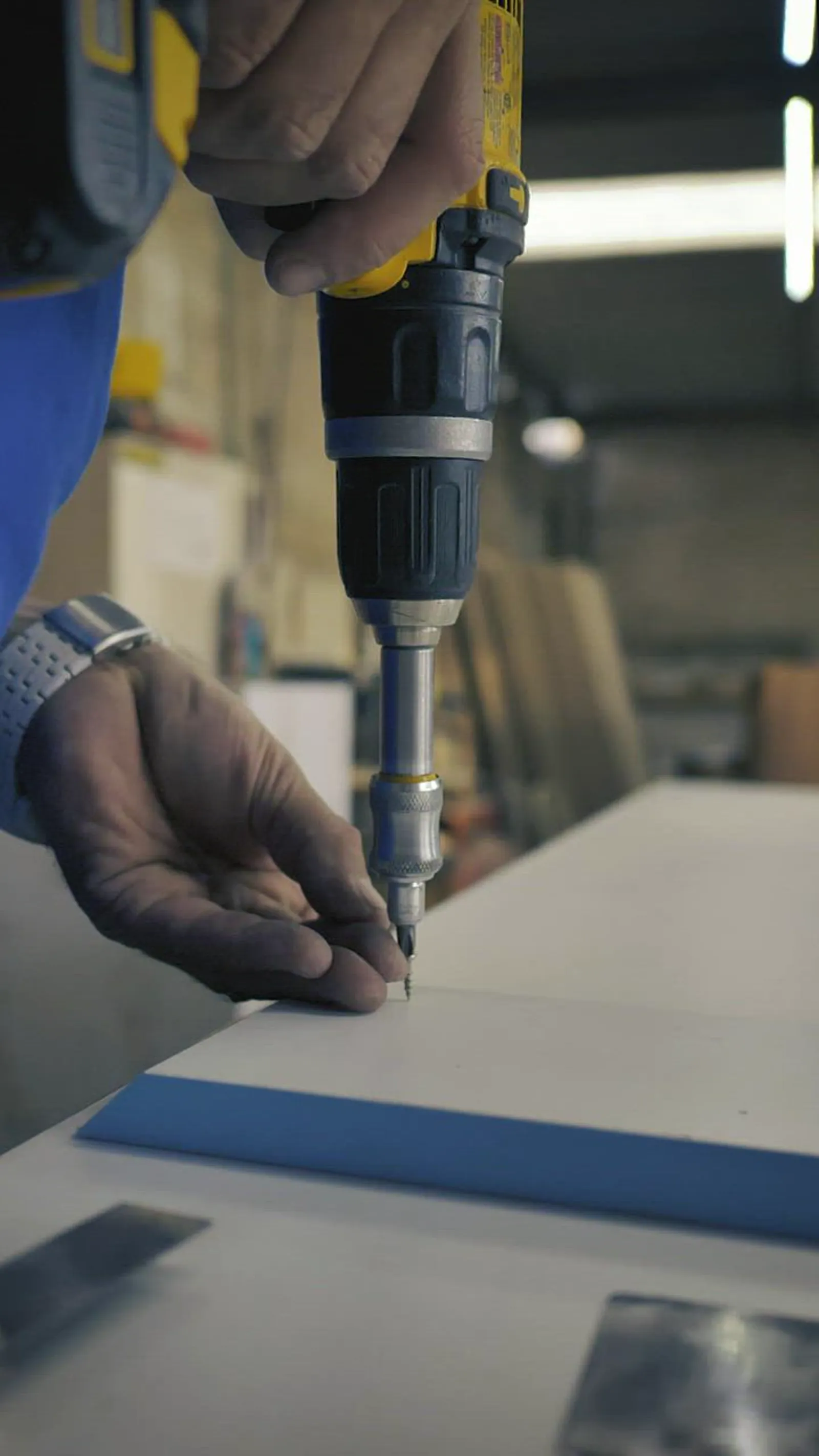 Worker driving a screw into a board with a cordless drill
