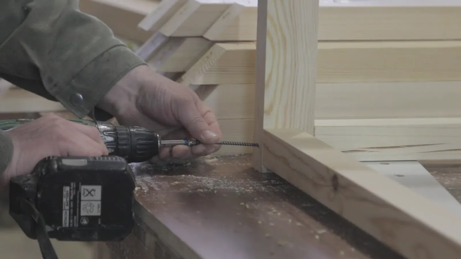 Carpenter driving a screw with a cordless drill while framing